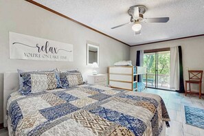 Ein Schlafzimmer mit einem großen Bett, einem Deckenventilator, einem Spiegel, einer Kommode und Blick ins Freie.