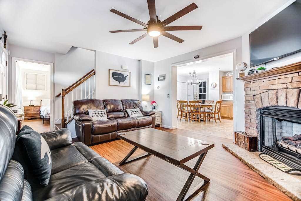 Un salon comprenant un canapé en cuir, une table basse, une cheminée et un coin repas avec des meubles en bois.