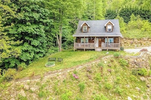 Eine Blockhütte mit Veranda, umgeben von dichtem Wald.
