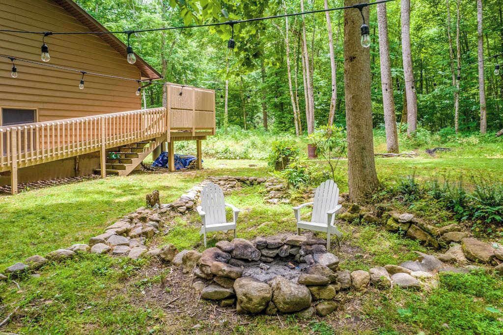 En hytte med terrasse, ildsted i sten og to Adirondack-stole.