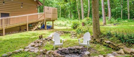 En hytte med terrasse, ildsted i sten og to Adirondack-stole.