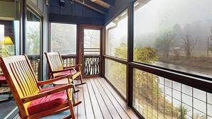 A covered porch with wooden chairs and a view of a river. - at E's please (Cullowhee)