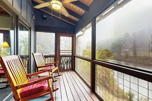 Eine überdachte Veranda mit Holzstühlen und Blick auf einen Fluss.