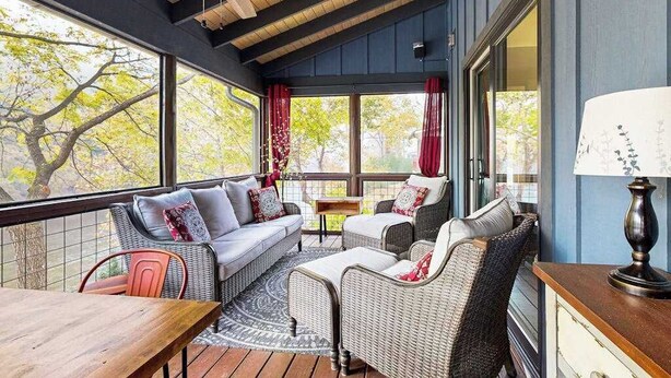 A cozy room with a wooden ceiling, large windows, wicker furniture, and a table. - at E's please (Cullowhee)
