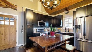 A kitchen with dark cabinets, stainless steel appliances, a wooden dining table, and benches. - at E's please (Cullowhee)