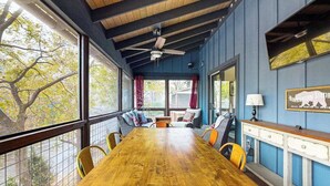 A dining area with a wooden table, chairs, a ceiling fan, and a view of trees through large windows. - at E's please (Cullowhee)