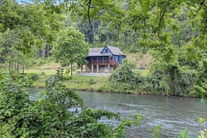 Ein Haus am Fluss, umgeben von viel Grün.