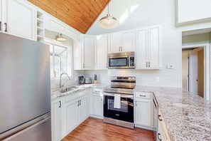 Une cuisine moderne avec des meubles blancs, des appareils en acier inoxydable et un plan de travail en granit.