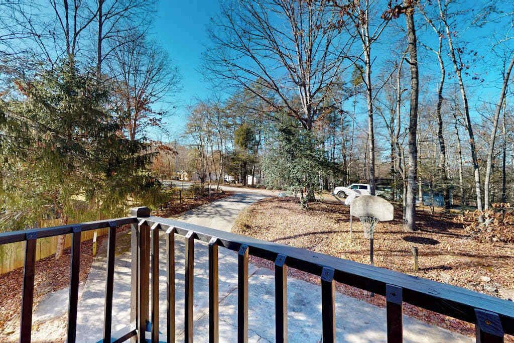 A pathway leading through a wooded area with a basketball hoop and a bench.