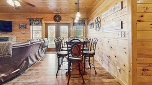 A wooden interior with a dining table and chairs, a leather couch, and a ceiling fan.