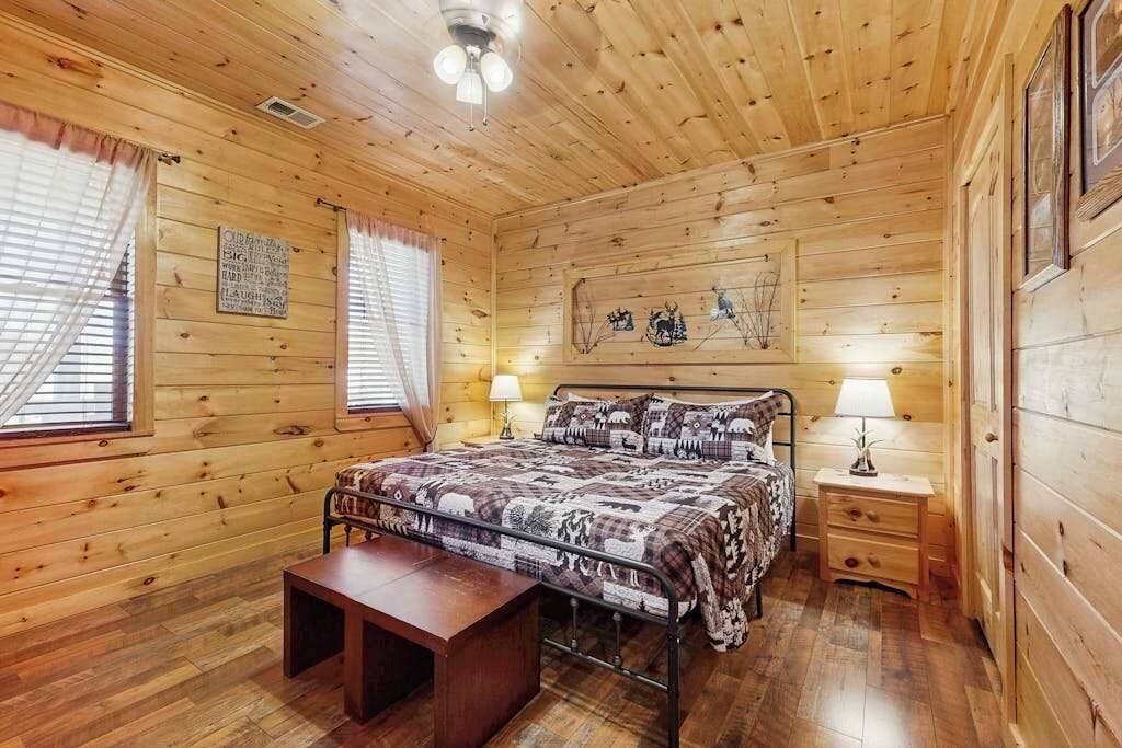 Een slaapkamer met houten lambrisering, een bed, nachtkastjes en een bankje.
