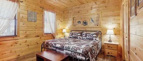 Een slaapkamer met houten lambrisering, een bed, nachtkastjes en een bankje.