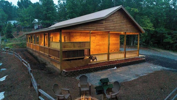 A wooden cabin with a porch, a fire pit, and outdoor seating.