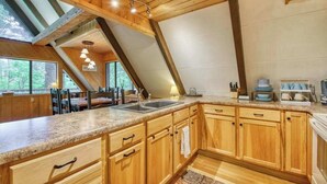 A kitchen with wooden cabinets, granite countertops, and a skylight. - Chalet at Peek's Creek (Franklin)