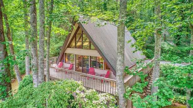 A cabin with a wooden deck, large windows, and a staircase leading to the upper level. - Chalet at Peek's Creek (Franklin)