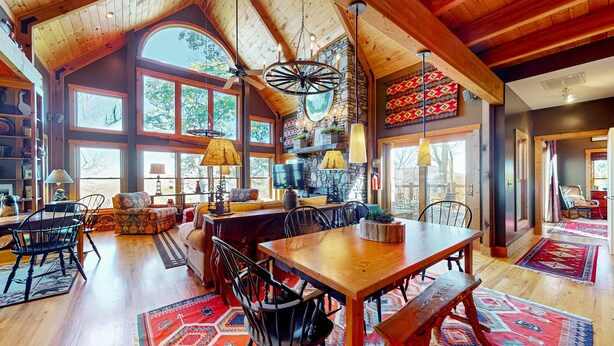 A spacious interior with a high ceiling, wooden beams, a large dining table, and multiple seating arrangements.