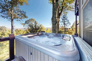 Ein Whirlpool auf einer Terrasse mit Blick auf Bäume und Berge.