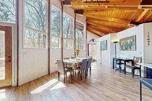 A spacious room with large windows, a wooden ceiling, and a dining area with a table and chairs. - Two-story, dog-friendly home with two kitchens, central AC, & gas fireplaces (Franklin)