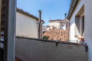 Ein schmaler Gang mit Terrakotta-Dachziegeln, einer sichtbaren Antenne und einer entlang des Gebäudes verlaufenden Metallrohr.