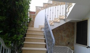 A staircase with beige steps, metal balusters, and a stone wall. - Apartment MOON DROP TWO at 300mt. sand (Lido Marini)