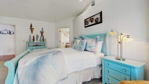 Un dormitorio con cama, mesita de noche, lámpara y adornos en la pared.