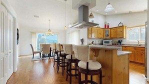 Una cocina moderna con armarios de madera, una isla central con taburetes de bar e iluminación colgante.