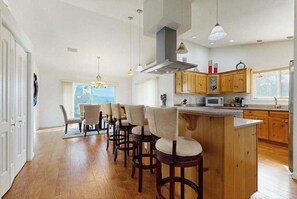 A modern kitchen with wooden cabinets, a central island with bar stools, and pendant lighting. - The Overlook Upper Retreat (Franklin)