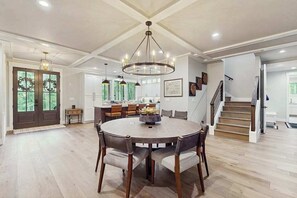 A spacious dining area with a round table, chairs, and pendant lighting. - The Fox Den (Cashiers)