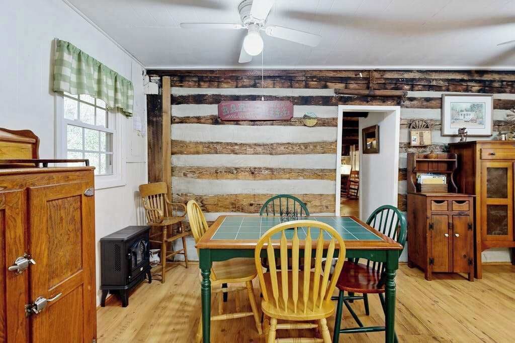 Un comedor rústico con una mesa de madera, sillas y una radio antigua.