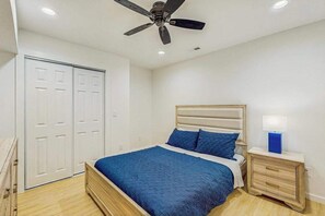A bedroom with a bed, a nightstand, a ceiling fan, and a wardrobe.