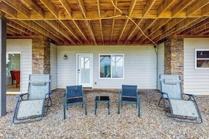 Un patio couvert avec quatre chaises, une table et un mur en pierre.