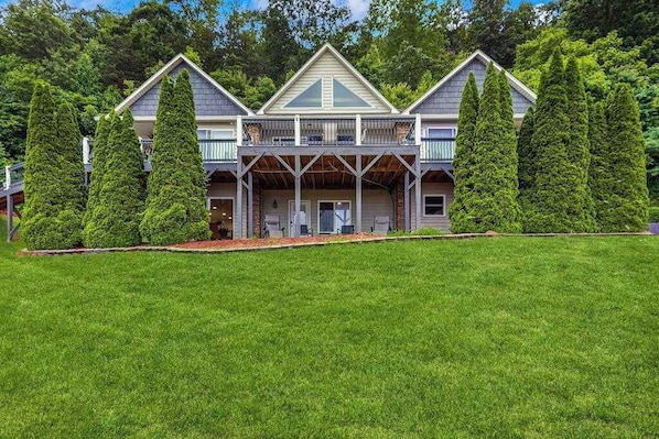 A two-story house with a covered porch, surrounded by a well-maintained lawn and tall trees.