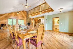 A spacious dining area with a wooden table and chairs, a stone fireplace, and a view of the outdoors. - Close to Heaven (Sylva)