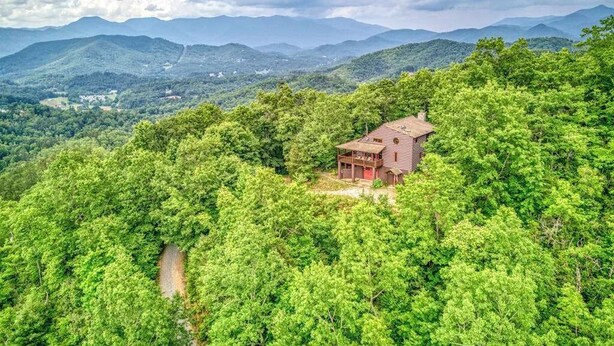 Eine Hütte, umgeben von dichtem Wald, mit freiem Blick auf entfernte Berge.