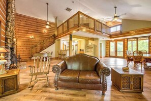 A spacious living area with a leather sofa, wooden furniture, and a staircase leading to an upper level. - Close to Heaven (Sylva)