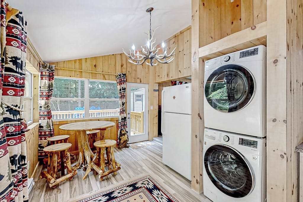 Un intérieur en bois avec un lave-linge, un lustre et une table avec des tabourets.