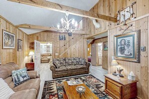 Un intérieur en bois avec un canapé, une table basse et un lustre.