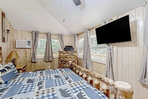 Ett rum med träpanel, en säng, en tv, ett fönster och en väggmonterad luftkonditioneringsanläggning.