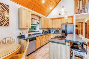 Eine moderne Küche mit Holzausstattung, einer Arbeitsplatte aus Granit und einem Edelstahlkühlschrank.