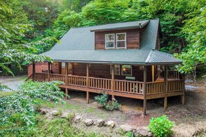 Eine Holzhütte mit Veranda, umgeben von dichtem Wald.