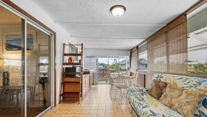 Un balcon spacieux avec un coin repas, un canapé agrémenté de coussins à motifs floraux et une vue sur le quartier.