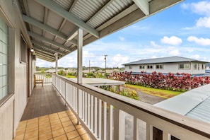 Ein überdachter Balkon mit Blick auf eine Wohngegend, inklusive eines Hauses und eines Gartens.