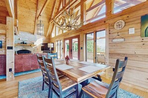 Ein Holzinterieur mit einem Esstisch, Stühlen, einer Deckenleuchte und einer Küchenzeile.