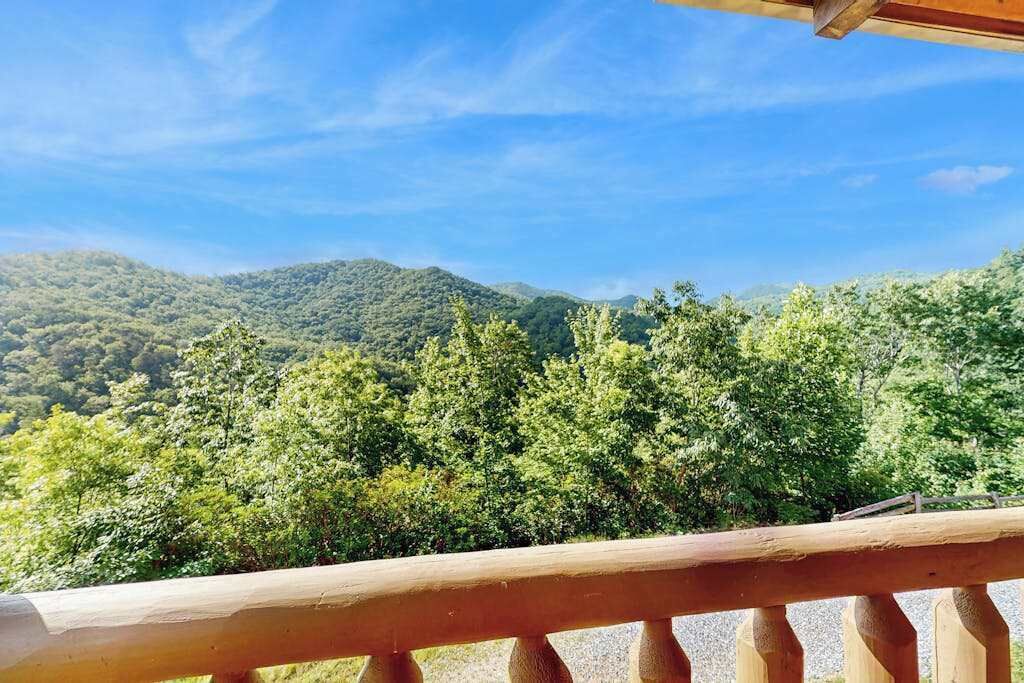 Une balustrade en bois surplombe une montagne couverte de forêts.