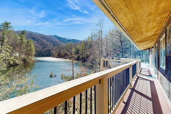 Eine Holzterrasse mit Blick auf einen Fluss und ein Wald.