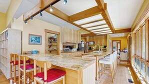 Una cocina amplia con vigas de madera, una isla central y taburetes de bar.