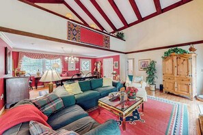 A spacious living room with a large sofa, a coffee table, and a dining area with chairs and a table.