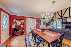 A dining room with a wooden table, chairs, a chandelier, and a fireplace.