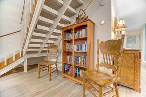 Eine Treppe mit hölzernen Geländern, ein Bücherregal voll mit Büchern und zwei Holzstühle.