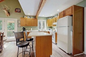 Eine Küche mit Holzausstattung, einem weißen Kühlschrank und einem Hirschkopf an der Wand.